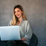 Young female designer, freelancer working in the office. Female using laptop to searching info.